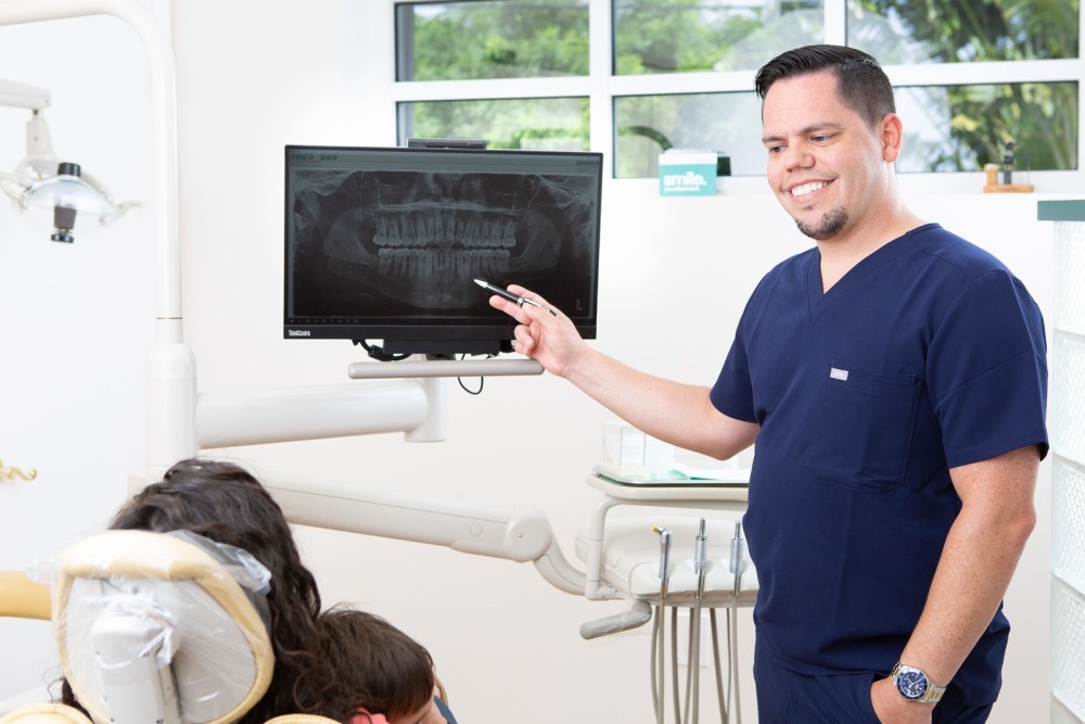 Dr. Cesar J. Hernandez explaining a dental X-ray to a patient in a modern dental office